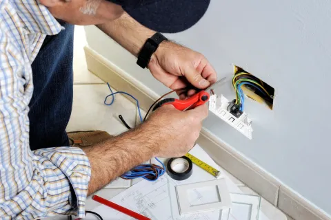 Electrician stripping the cable to connect switches and sockets of a residential electrical installation
