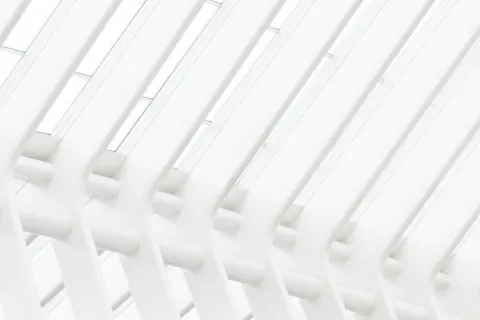 Modern architectural ceiling with repeating white ribs and skylights creating a bright geometric pattern