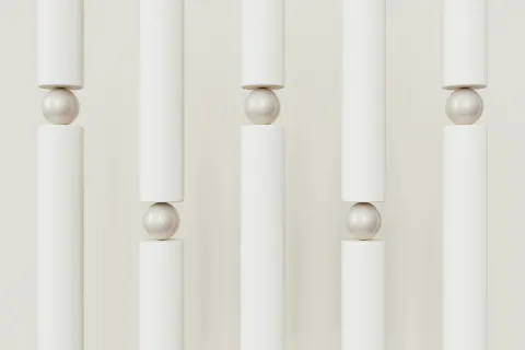 Vertical white cylinders balanced on white spheres creating a minimal geometric pattern with soft shadows.