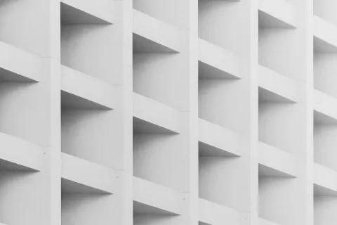 Close-up of a modern building facade with repeating white concrete triangular balconies in a geometric pattern