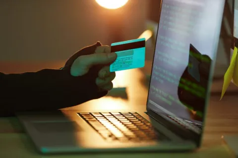 a hand holding a card over a laptop