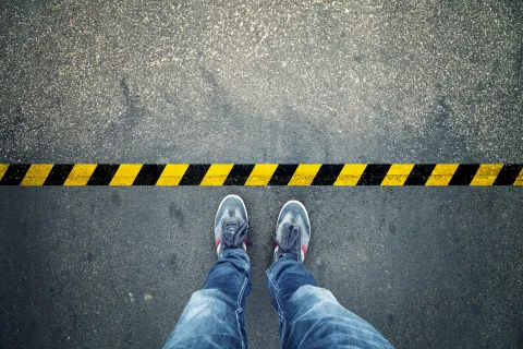 a person's legs and feet on a yellow and black striped surface