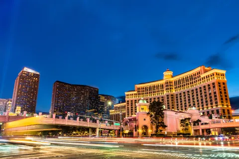 Night view of Las Vegas Strip with illuminated Bellagio Hotel and moving traffic lights under a deep blue sky