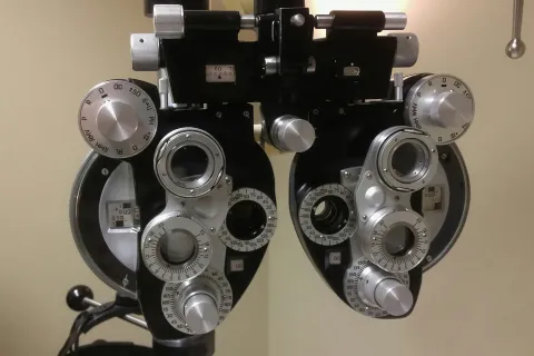 Close-up of a phoropter, an eye exam device with dials and lenses for vision testing.