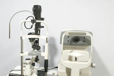 Close-up of ophthalmic examination equipment including a slit lamp and autorefractor on a white background.