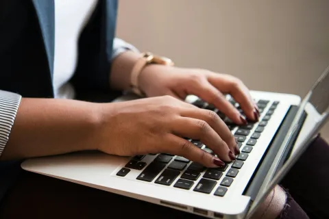 Close-up of hands typing on a laptop keyboard, showcasing modern working environment and productivity.