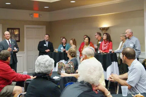 Business networking event with professionals attentively listening to a speaker in a conference room.