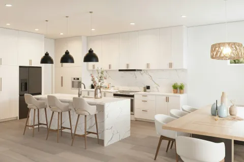 Bright modern kitchen with white cabinetry, marble island, black pendant lights, and a wooden dining table with white chairs.