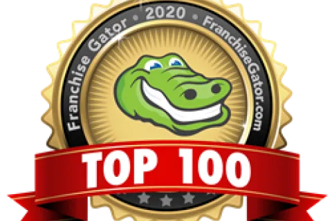 Gold badge with green alligator logo and red ribbon stating Top 100 by Franchise Gator 2020