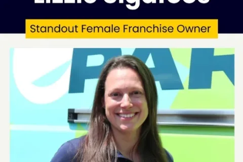 Portrait of Lizzie Sigafoos, standout female franchise owner, smiling in front of branded background.