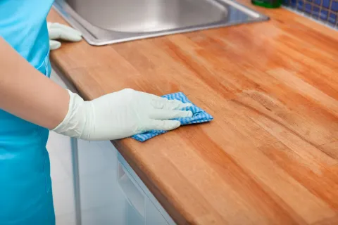 a person's hand with gloves on a wooden table
