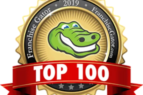 Gold seal with smiling green alligator and red ribbon reading TOP 100, Franchise Gator 2019 award emblem