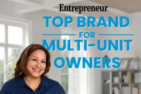 Smiling woman in navy polo with Mold Pro logo stands in modern living room with award text overlay