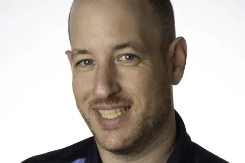 Smiling man wearing a navy blue MaidPro polo shirt with logo on a white background in a studio portrait.