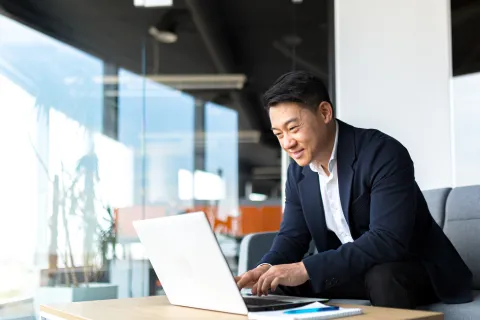 a man sitting on a couch and working on a laptop