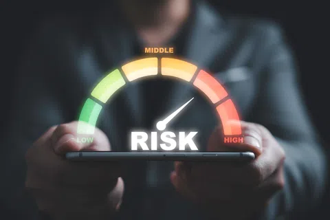 Close-up of hands holding a smartphone with a risk meter gauge pointing to high risk in red zone.