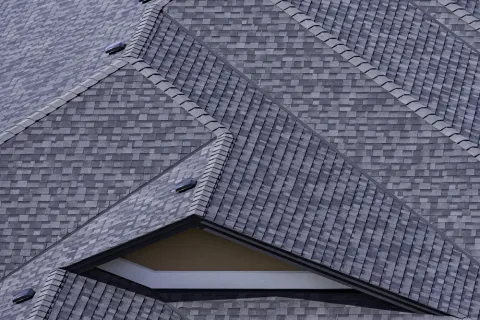 Close-up of a grey shingled house roof with multiple intersecting slopes and vents.
