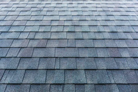 Close-up of a blue-gray asphalt shingle roof featuring layered, textured rectangular shingles.