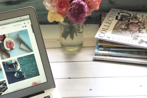 a desk with a laptop and a vase of flowers on a table