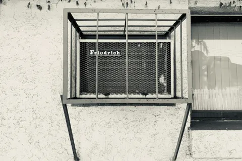A black and white photo of a Friedrich air conditioner unit on a textured wall.