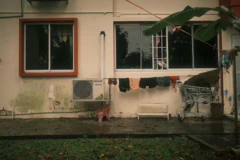 A laundry line with clothes hangs outside a building with a shopping cart nearby.