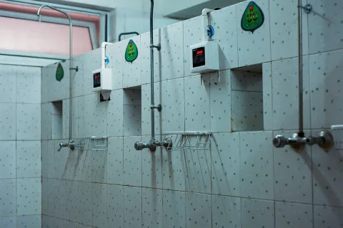 Clean shower area featuring multiple showerheads and tiled walls, ideal for public or communal spaces.