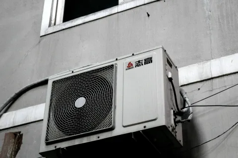 A mounted air conditioning unit on a gray building exterior.