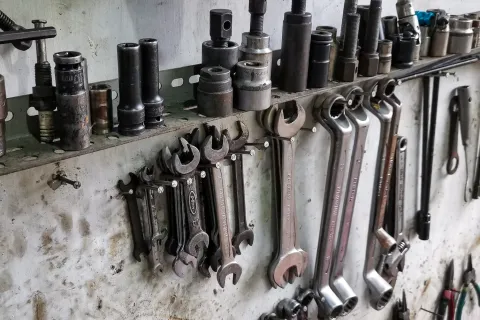 A close-up of various hand tools neatly organized on a workshop wall, including wrenches and sockets.