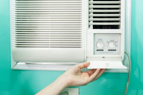Close-up of an air conditioning unit's control panel and filter access being opened.