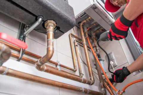 A plumber works on copper pipes and fittings under a sink, ensuring proper installation and maintenance.