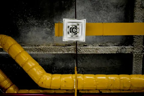 Abstract industrial ceiling view with yellow ducts and alternating textures and patterns.