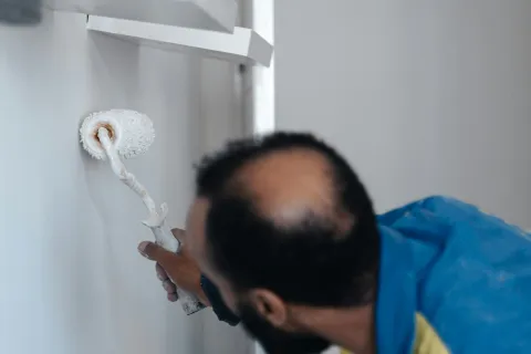 A man painting a wall with a roller, showcasing a clean and modern home renovation scene.