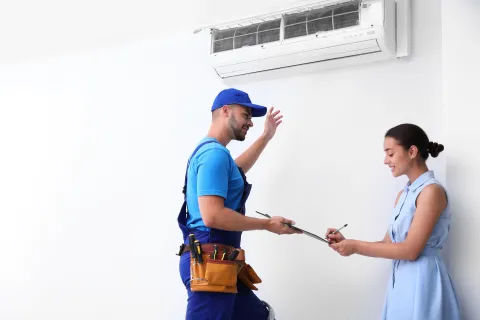 Air conditioning technician explaining service to a customer in a modern home setting.