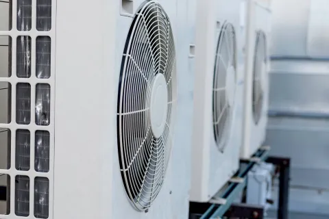 Close-up of outdoor air conditioning units with visible fans and metal casing.