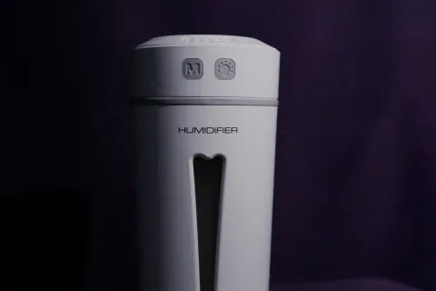 Compact white Homgeek humidifier with control buttons and water level window on dark background
