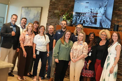 Coosa Valley Credit Union team members posing in office with stone fireplace and screen in background