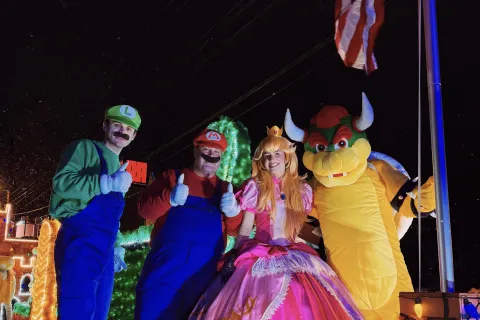 Four people dressed as Mario, Luigi, Princess Peach, and Bowser from Super Mario, posing outdoors at night.