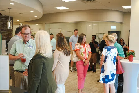 People socializing in a modern indoor space with casual attire and drinks during a networking event.