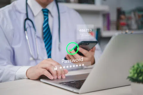 Doctor using laptop and phone with digital password security and two-factor authentication interface.