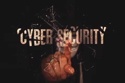 Finger touching shattered glass over the words Cyber Security symbolizing protection and digital threats