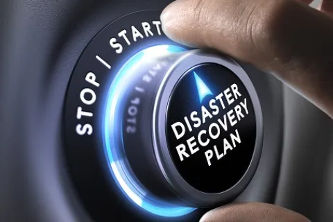Close-up of hand turning a knob labeled Disaster Recovery Plan with a glowing blue ring.