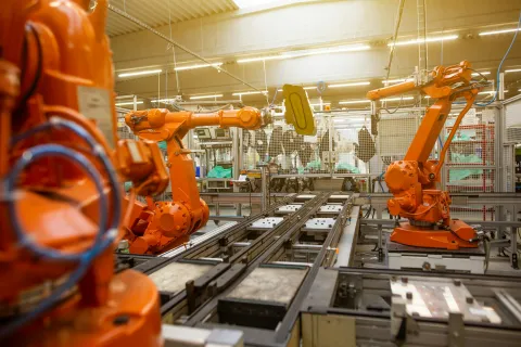 Industrial robotic arms operating on automated assembly line in a bright manufacturing facility.