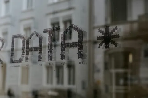 Close-up of the word DATA created with small round dots on a glass window reflecting a building exterior.