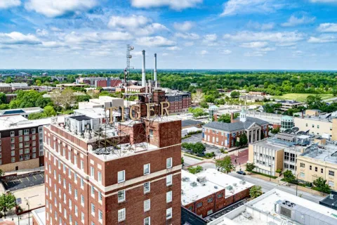 Aerial view of a cityscape with the Tiger sign on a brick building under a partly cloudy sky.
