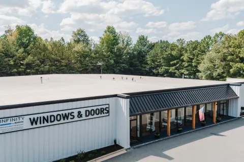 Exterior view of Infinity Windows & Doors store with clear signage and surrounding trees under a blue sky.