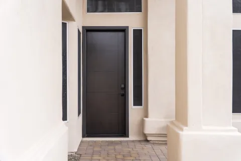 Modern black front door with side and top narrow windows and beige stucco exterior walls
