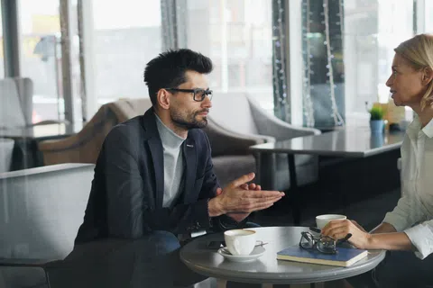 Two business professionals having a focused discussion over coffee in a modern office lounge area.