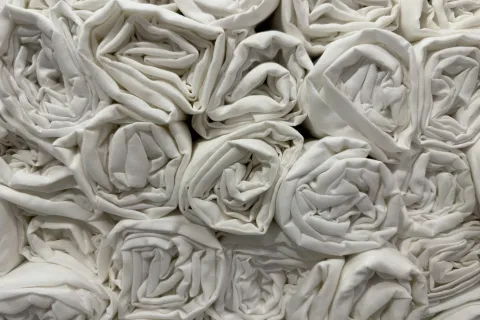 Close-up of neatly rolled white fabric pieces stacked together in a grid pattern.