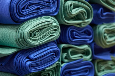 Close-up of neatly rolled blue and green fabric towels stacked in rows, showing texture and color contrast