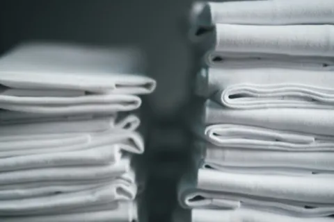 Stacks of neatly folded white fabric towels arranged closely with soft lighting.